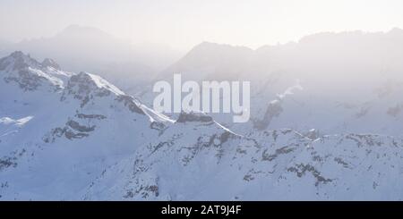 Schichten von schneebedeckten Berggipfeln im Winter mit Licht durch Nebel und Nebel - Blick von Terrazza Delle Dolomiti bei Funivia Sass Por Stockfoto