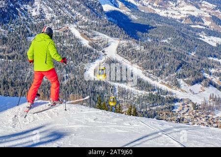 Alta Badia, Italien - 21. Januar 2020: Skifahrer, die sich auf eine rote Skipiste über dem Dorf La Villa, Südtirol, in den Dolden, Italien, vorbereiten. Stockfoto