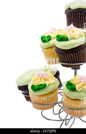 Sortiment an Cupcakes mit pastellfarbenem Buttercremefeising in einem silberfarbenen Cupcake-Halter in Zwingerfarbe. Isoliert auf weißem Hintergrund. Stockfoto