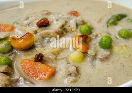 Extremer Closeup von Chicken Stew Curry garniert mit geröstetem Cashew und Rosinen Stockfoto