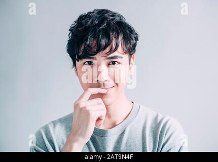 Porträt eines jungen lächelnden gutaussehenden Mannes isoliert auf grauem Hintergrund Stockfoto
