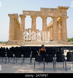 Frau sitzt, um den Tempel im Archäologischen Park Selinunte, Sizilien, Italien, zu sehen. Selinunte war eine der bedeutendsten der griechischen Kolonien auf Sizilien Stockfoto