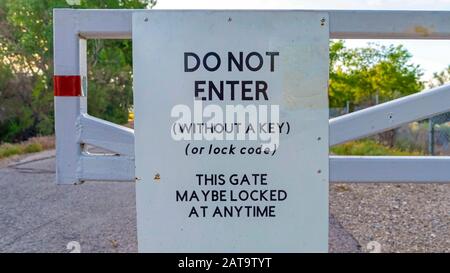 Panorama-Rahmen nicht betreten Schild auf einem weißen Tor gegen Straßenbäume und bewölkten Himmel montiert Stockfoto