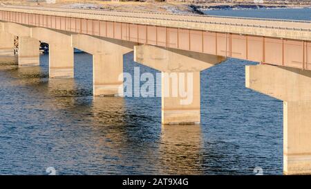 Panorama Stringer Brücke über ruhigen See mit Blick auf verschneite Land und wolkenbedeckten Himmel Stockfoto