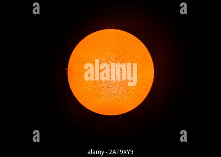 Ein Blick auf die Sonnenscheibe mit einem H Alpha-Teleskop. Einige Fackeln, die aus der Sonnensphäre am Gliedmaßen ausgehen, konnten wie rote Fackeln gesehen werden Stockfoto