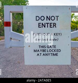 Square nicht betreten Schild auf einem weißen Tor gegen Straßenbäume und bewölkten Himmel montiert Stockfoto