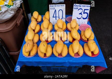 Gelbe Mangos zum Verkauf auf einem Freiluftmarkt in Chiang Mai, Thailand, mit Preisen in Baht (thailändische Währung). Stockfoto