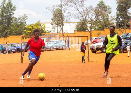 Mädchen, die auf einem Spielplatz gegenüber dem Centre Culturel Islamique Nyamirambo (Kwa kadhafi) in Kigali, Ruanda Fußball spielen. Stockfoto