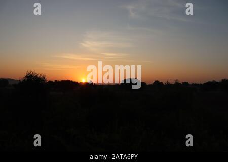Foto im Querformat von Silhouette bei Sonnenaufgang mit Sonne Stockfoto