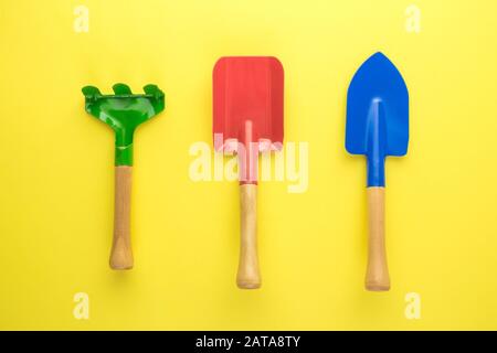 Flaches Lay von Kleingartenwerkzeugen auf gelbem Hintergrund minimales kreatives Konzept. Stockfoto