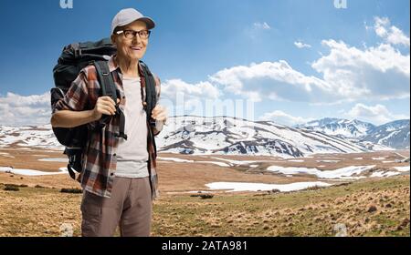 Älterer männlicher Wanderer mit Rucksack, der auf einem Berg mit Schnee klettert Stockfoto