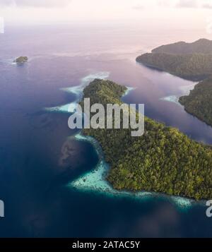 Von oben gesehen sind die vielen tropischen Inseln im indonesischen Raja Ampat von gesunden Korallenriffen und hoher mariner Biodiversität umgeben. Stockfoto