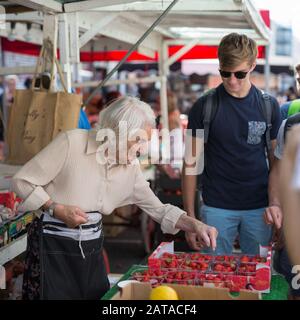 Old Greengrocer Lady mit weißem Haar, die Obst auf dem Portobello Road Market in London verkauft. Stockfoto