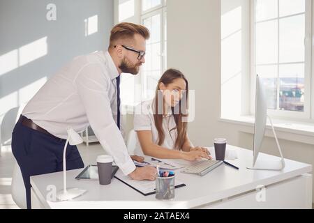 Ein positiver Geschäftsmann und eine Geschäftsfrau, die in einem weißen Büro zuversichtlich arbeitet. Stockfoto