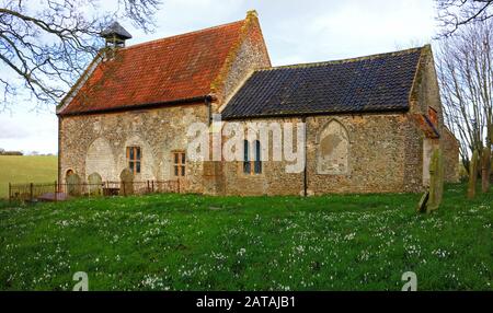 Blick auf die winzige Allerheiligenkirche mit Snowdrops, Galanthus nivalis, im Dorf Waterden, Norfolk, England, Großbritannien, Europa. Stockfoto