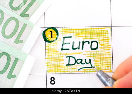 Frauen-Finger mit Stift Schreiben Erinnerung Euro-Tag im Kalender mit 100 Euro Banknote. Januar 01. Stockfoto