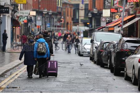 Touristen mit Reisetaschen gehen die South Anne Street in Dublin hinunter Stockfoto