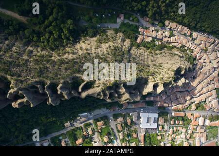 VERTIKALE LUFTANSICHT. Provenzalisches Dorf am Fuße einer seltsam geformten Felsformation. Les Mées, Provence, Frankreich. Stockfoto