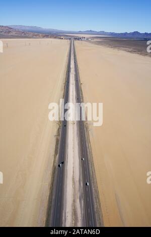 LUFTAUFNAHME. Ein langer Abschnitt der Interstate 15, der die playa des Ivanpah Dry Lake in Richtung Primm überquert. Nipton, San Bernardino County, Kalifornien, USA. Stockfoto