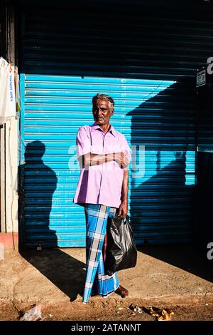 Ein lokaler Kerl in blauem Kleid, der an der Seite der Straße in Sri Lanka steht. Stockfoto