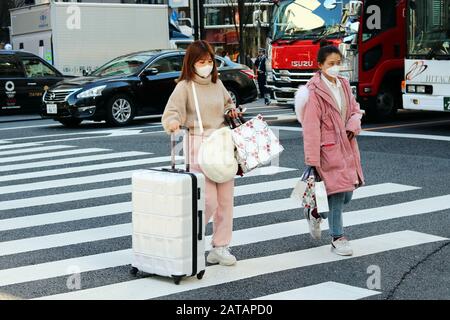 Besucher, die Gesichtsmasken tragen, überqueren eine Hauptstraße im Tokioter Stadtteil Ginza. (Jan. 2020) Stockfoto