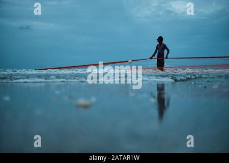 Fischer zieht die Netze am Strand in Sri Lanka aus dem Meer. Die Stadt Trincomalee hat einen großen und langen Strand, an dem die Einheimischen Netze und Fische ziehen. Stockfoto