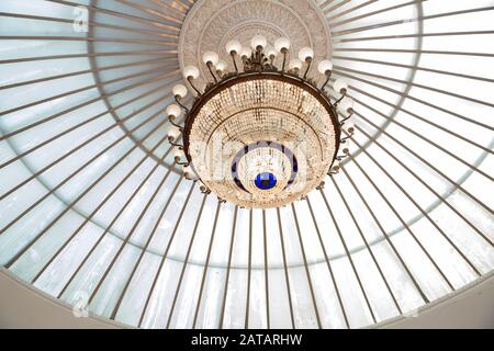 Runder Deckenleuchter . Runde Form des Kronleuchters . Lampe im Tagungsraum . Luxus-Kronleuchter mit Kristallanhängern. Ein großer vergoldeter Kronleuchter hängt Stockfoto