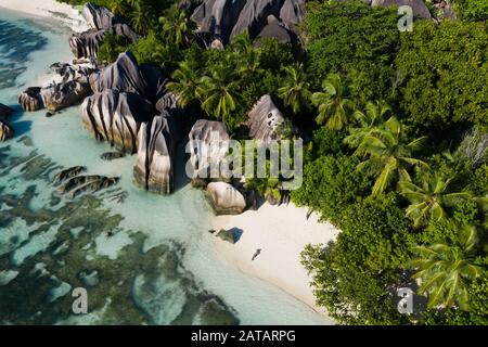 Touristen an einem schönen Strand mit weißem Sand auf einer tropischen Insel auf den Seychellen - Dem berühmten Strand von Anse d'Argent in La Digue Stockfoto