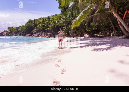 Touristen an einem schönen Strand mit weißem Sand auf einer tropischen Insel auf den Seychellen - Dem berühmten Strand von Anse d'Argent in La Digue Stockfoto