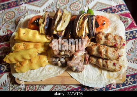 Lavash und Kebab an Bord. Aserische Kebab wird mit lula kabab serviert. Fleisch, Kartoffeln, Tomaten, Auberginen. Stockfoto