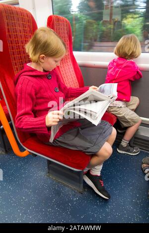 Neun Jahre altes Mädchen im Sitz Kinder/Kinder/Kinder lesen eine kostenlose Morgenzeitung/Zeitung, während sie im Zug nach London UK England UK sitzen. (112) Stockfoto