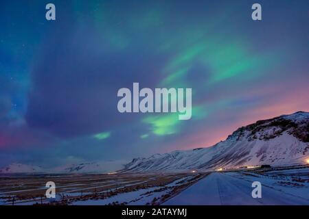 Wundervolle Nordlichter, schöner Blick auf einen bunten Himmel über schneebedeckten Hochbergen, wundervolle Natur Islands Stockfoto