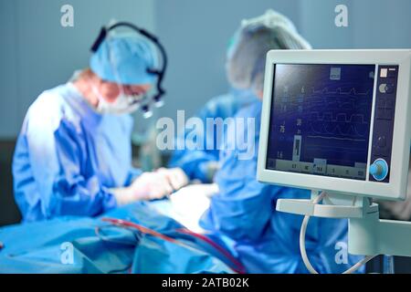 Elektrokardiogramm im Krankenhaus Chirurgie operative Notaufnahme, die Herzfrequenz des Patienten mit blur Team von Chirurgen Hintergrund. Stockfoto