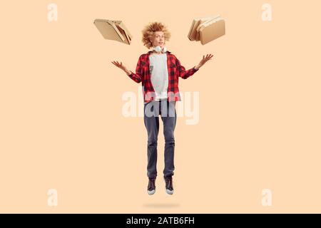 Junger Mann springt mit Kartonpizzakisten hoch Stockfoto