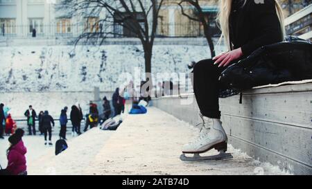 Eine junge Frau, die vor einer Eisbahn sitzt Stockfoto