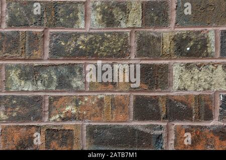 Horizontaler Nahbereich einer verwitterten, mehrfarbigen Ziegelwand; Hintergrund. Stockfoto