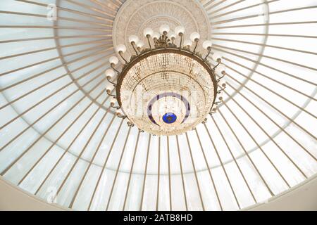 Runder Deckenleuchter . Runde Form des Kronleuchters . Lampe im Tagungsraum . Luxus-Kronleuchter mit Kristallanhängern. Ein großer vergoldeter Kronleuchter hängt Stockfoto