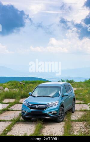 Mnt. Runa, Ukraine - May 22, 2019: Blau suv auf einer gepflasterten Wiese. Beliebte AWD Fahrzeug in der Natur Landschaft. stürmisches Wetter mit bewölktem Himmel. Ihrer Familie Stockfoto