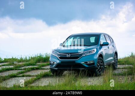 Mnt. Runa, Ukraine - May 22, 2019: Blau suv auf einer gepflasterten Wiese. Beliebte AWD Fahrzeug in der Natur Landschaft. stürmisches Wetter mit bewölktem Himmel. Ihrer Familie Stockfoto