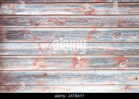 Holzhintergrund. Rosafarbene Flecken auf der verwitterten grauen Holzplankenwand Stockfoto