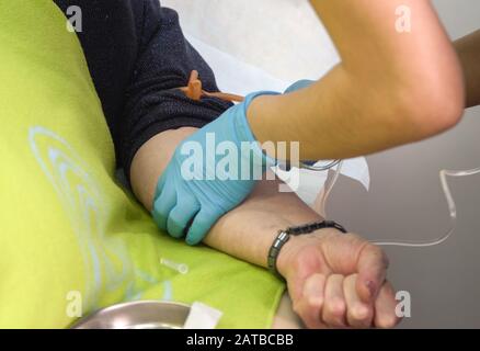 Der Arzt stellt den Patienten auf einen Tropfer mit Kochsalzlösung und Antibiotika. Die Pflegekraft verabreicht dem Patienten eine Injektion Stockfoto