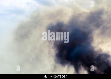 Auspuffrohr des Fährschiffs mit schwarzem dichtem Rauch, der herauskommt, und Himmel mit Wolken auf dem Hintergrund. Luftverschmutzung. Stockfoto