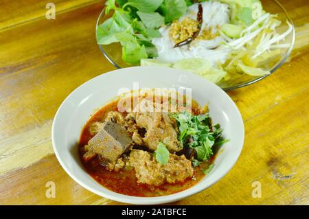 Reisnudeln und frisches Gemüse essen mit würzigem Schopfschwein und roter Baumwollbaumsoße mit Knochen Stockfoto