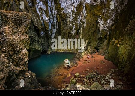 Einheimische in einer Brackwasserhöhle auf der Panasia-Insel, Papua-Neuguinea. Am Fuß der Höhle vermischt sich Meerwasser mit frischem Regenwasser, das als Trinkwasser in einem Tank gesammelt wird Stockfoto