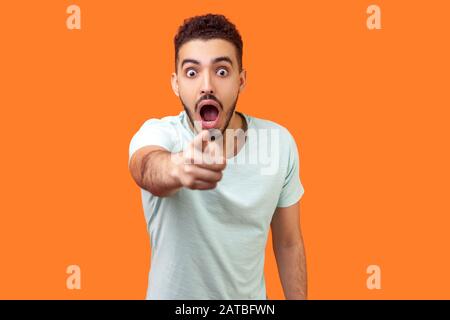 HE, du! Porträt des verblüfften brünetten Mannes mit Bart in legerer weißer T-Shirt, der mit dem Finger auf die Kamera zeigt und mit staunendem schockiertem Ausdruck aussieht. Stockfoto