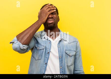 Facepalm, habe ich vergessen. Porträt des bedauernshaften Mannes im Jeanslegeren Hemd, das Hand im Gesicht hält, Trauer und Verzweiflung über das Scheitern, seine Schuld. IND Stockfoto