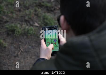 Ein junger, dunkelhaariger Junge von 12 in Brille spielt Pokemon Go Walking auf einem iPhone-Mobilgerät Stockfoto