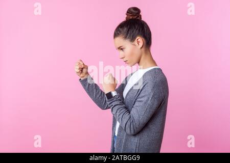 Seitenansicht des tapferen Teenagermädchens mit bunter Frisur in lässiger Kleidung in defensiver Haltung mit erhobenen Fäusten, bereit zum Durchschlag, ausblickend Aggressi Stockfoto