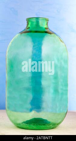 Ein 10-Liter-Glasbecher besteht aus dickem grünem Glas auf blauem Grund. Stockfoto