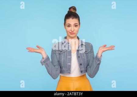 Ich weiß nicht, wen es interessiert. Porträt einer verwirrten, unsicheren Frau mit Haarbun in modischen Kleidungsstücken, die Schultern mit unvorsichtiger Indifferentierung zurechtschütteln Stockfoto